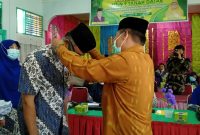 Kakan Kemenag Tanah Datar H Syarul mengalungkan tanda peserta kepada salah seorang guru.

