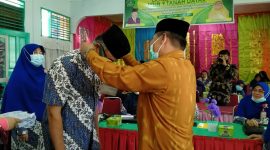 Kakan Kemenag Tanah Datar H Syarul mengalungkan tanda peserta kepada salah seorang guru.

