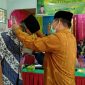Kakan Kemenag Tanah Datar H Syarul mengalungkan tanda peserta kepada salah seorang guru.

