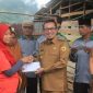 Bupati Tanah Datar Eka Putra menyerahkan bantuan krpada salah satu korban angin beliung Padangganting.
